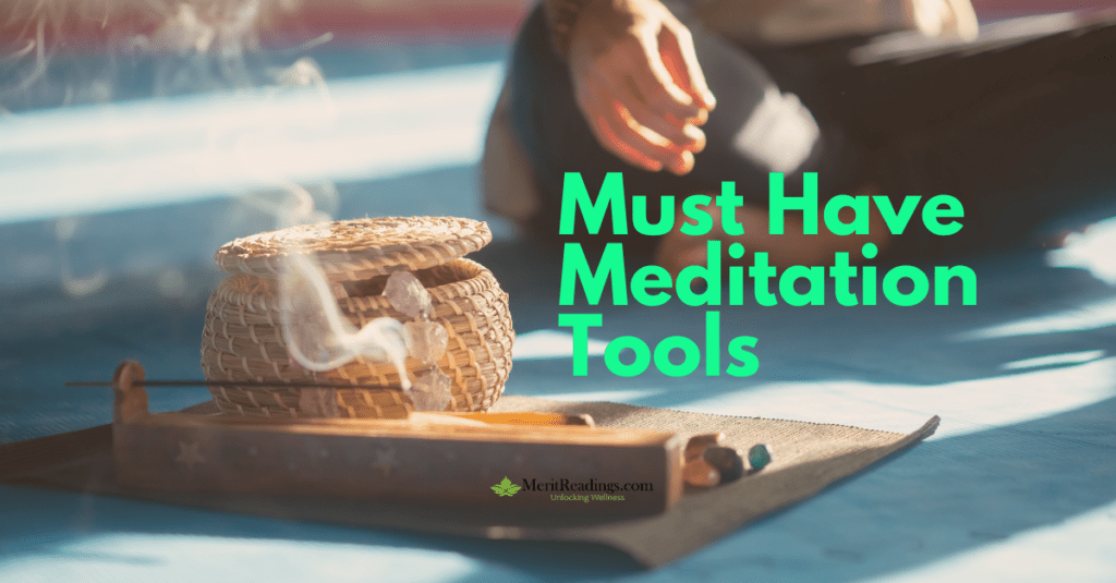 A serene setup featuring meditation tools including a wicker basket, incense sticks with smoke rising, and crystals on a wooden tray. The text "Must Have Meditation Tools" is prominently displayed in green, with a subtle logo and tagline reading "MeritReadings.com - Unlocking Wellness" at the bottom. A person is partially visible in the background, sitting cross-legged on a yoga mat.