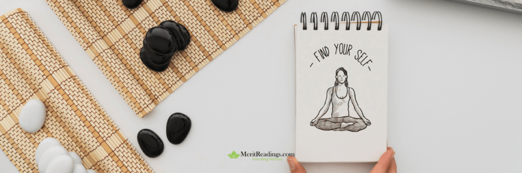 A sketch of a meditating woman in a lotus position on a notepad with the phrase "Find Your Self," surrounded by black and white stones on a woven mat.
